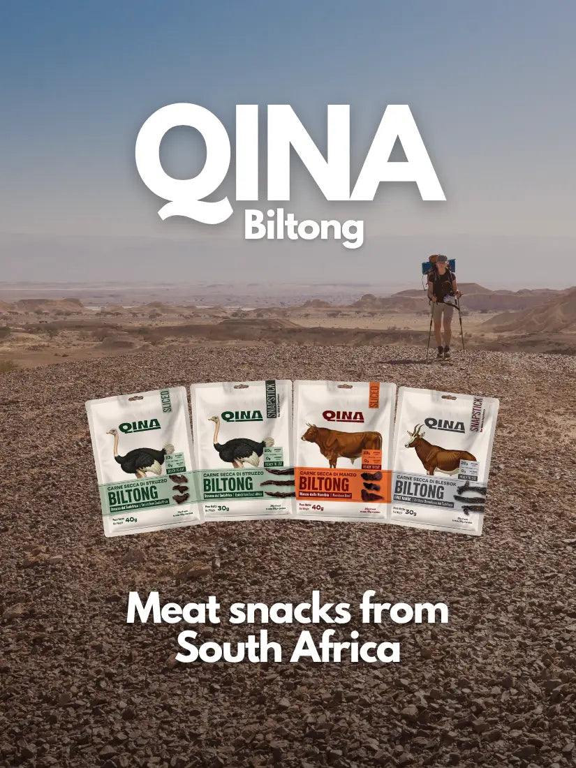 QINA Biltong packages displayed in a desert landscape with a person in the background.